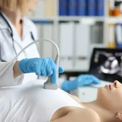 Lekarka wykonuje badanie USG piersi, by wyjaśnić wątpliwości po mammografii. Obraz z monitora pokazuje szczegóły.
