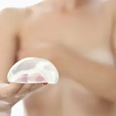 Dłoń trzyma implant piersiowy, symbol nadziei na rekonstrukcję piersi po chorobie.