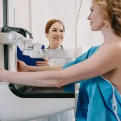 Kobieta na mammografii, pielęgniarka z uśmiechem obok. Co dalej po złym wyniku mammografii?