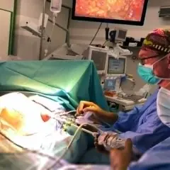 Chirurdzy podczas operacji, która może być przykładem tego, co to jest mastektomia. Na ekranie widać obraz z wnętrza ciała.