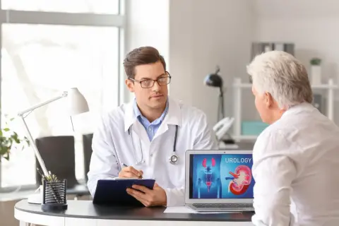 Lekarz omawia z pacjentem wyniki badań, na ekranie laptopa widoczny schemat układu moczowego, wskazujący na brodawkowaty rak urotelialny high grade.