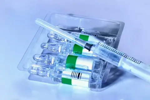 Zastrzyk po chemioterapii. Kilka ampułek leku w opakowaniu, obok leży strzykawka.
