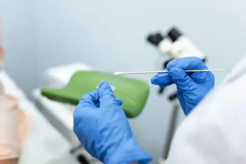 Ręce w niebieskich rękawiczkach przygotowują próbkę do analizy. Wynik biopsji tarczycy kategoria 3 jest kluczowy dla dalszego leczenia.