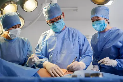 Chirurdzy w maseczkach i fartuchach operują. Czas jest kluczowy, gdy trzeba szybko operować raka.