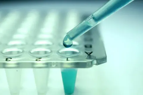 Kropla błękitnego płynu z pipety wpada do probówki. Czy leczenie biologiczne to chemia? Badania laboratoryjne pomagają odpowiedzieć na to pytanie.