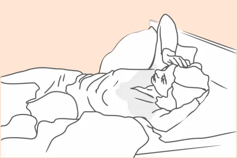 Osoba leży w łóżku, dotykając czoła, być może zmagając się z nocnymi potami po chemioterapii.