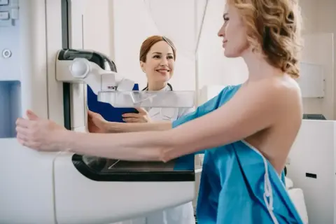 Kobieta na mammografii, pielęgniarka z uśmiechem obok. Co dalej po złym wyniku mammografii?