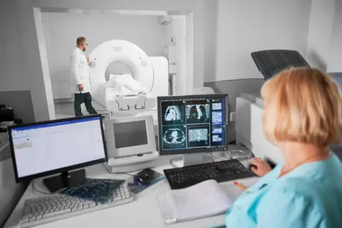 Lekarz nadzoruje badanie tomografem komputerowym, podczas gdy technik analizuje obrazy na monitorze. Czy tomografia komputerowa wykryje raka?
