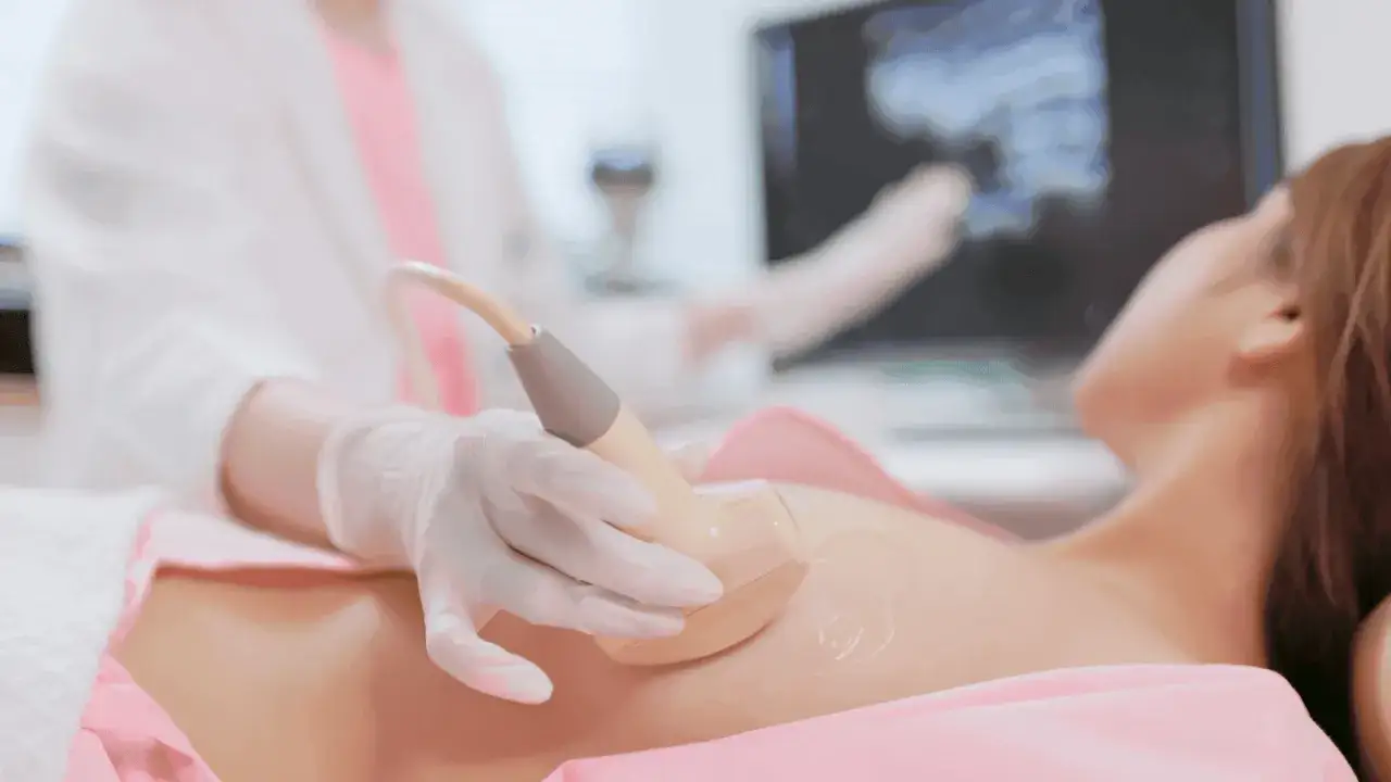 Lekarz wykonuje usg piersi w ciąży, badając przyszłą mamę. Na ekranie widać obraz ultrasonograficzny.